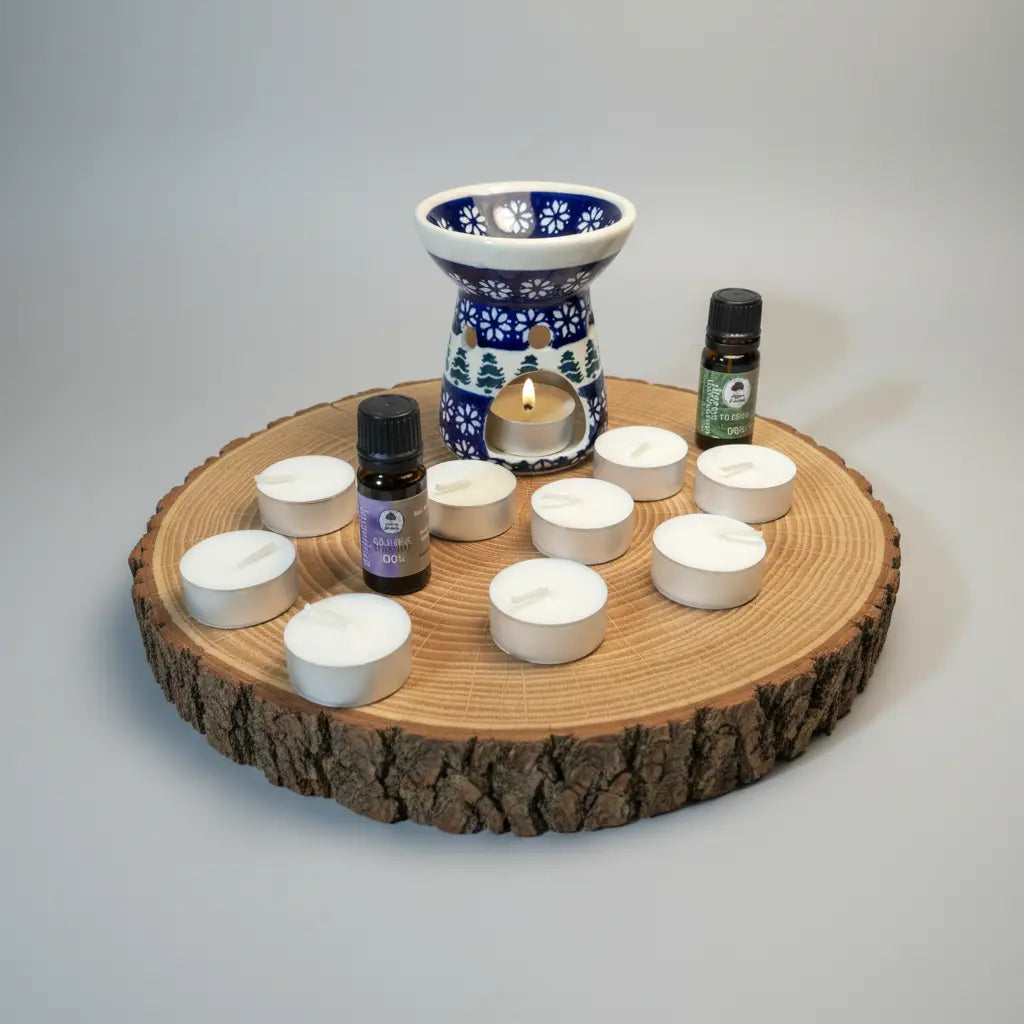 Kompletny Zestaw Ciepła Christmas hearth z 2 olejkami eterycznymi i 10 świeczkami typu Tealight znajdujący się na dębowym kawałku drewna w studyjnym oświetleniu 